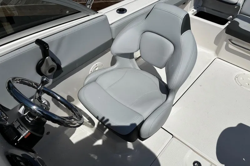 Slide: The Image of 2025 Robalo R207 Dual Console boat interior with steering wheel and cushioned seat. - 11
