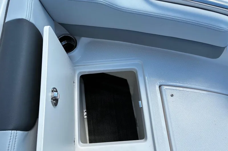 Slide: The Image of 2025 Robalo R207 Dual Console storage compartment with open hatch and cup holder. - 15