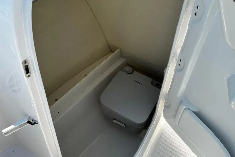 Slide: The Image of 2025 Robalo R207 Dual Console boat interior with compact portable toilet. - 16