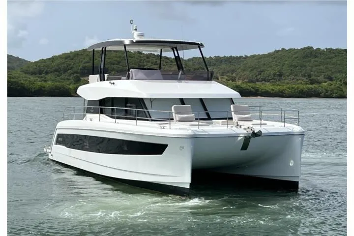 The Image of 2024 Fountaine Pajot MY6 yacht cruising on a serene waterway with lush green hills. - 1