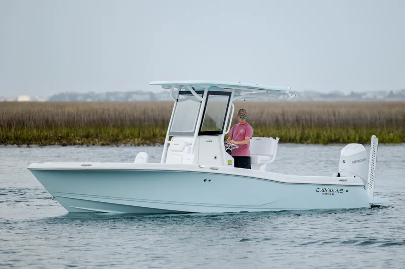 Slide: The Image of 2026 Caymas 24 HB boat cruising on water with person at helm. - 3
