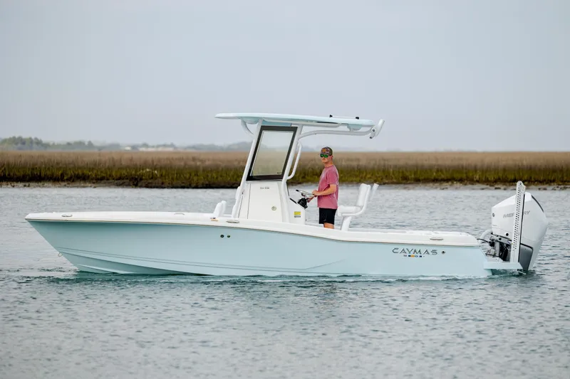Slide: The Image of 2026 Caymas 24 HB boat on water with person steering, featuring sleek design and modern outboard motor. - 4