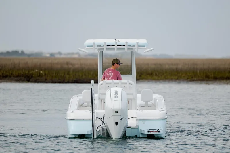 Slide: The Image of 2026 Caymas 24 HB boat on water, person steering, marshland background. - 6