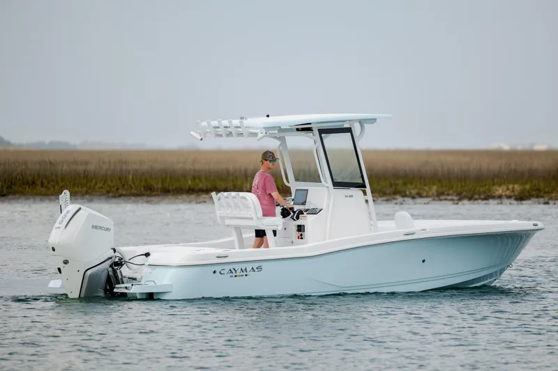 Slide: The Image of 2026 Caymas 24 HB boat on water with Mercury engine, person steering. - 8