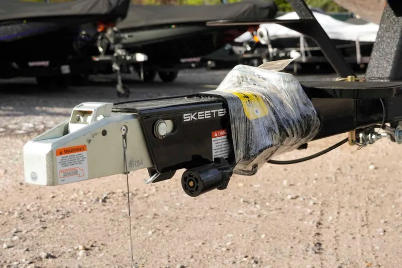 Slide: The Image of Trailer hitch of 2026 Skeeter ZXE20 boat, wrapped and secured, on gravel surface. - 46