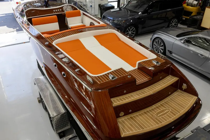 Slide: The Image of 2025 Comitti Venezia V28 luxury boat with orange and white seating in a showroom. - 2