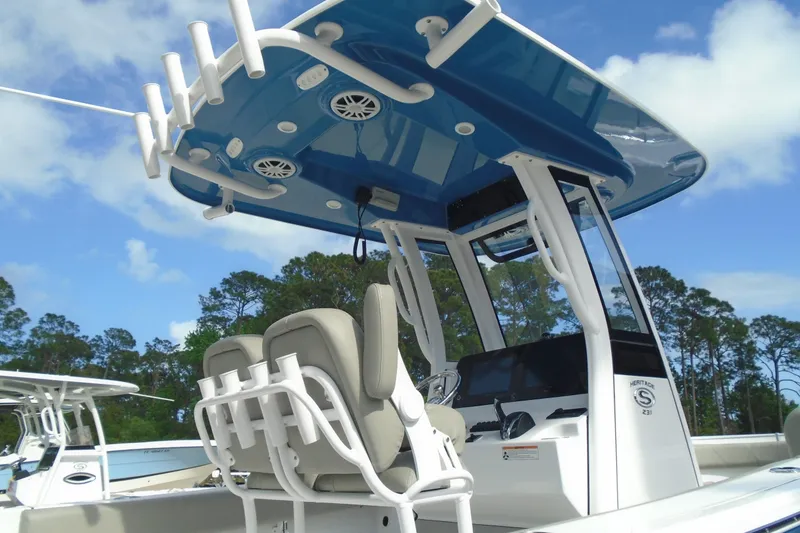 Slide: The Image of 2024 Sportsman Heritage 231 Center Console boat with T-top and seating, under blue sky. - 3