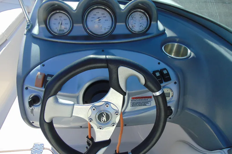Slide: The Image of Steering wheel and dashboard of a 2009 Monterey 214FS boat with gauges and controls. - 16