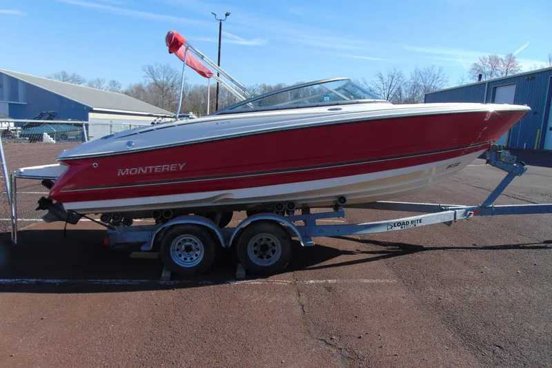 Slide: The Image of 2009 Monterey 214FS boat on trailer, red and white design, parked outdoors. - 4