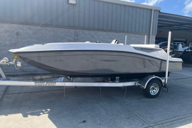 Slide: The Image of 2026 Starcraft SV 18 OB boat on trailer, parked outside a marine facility. - 2