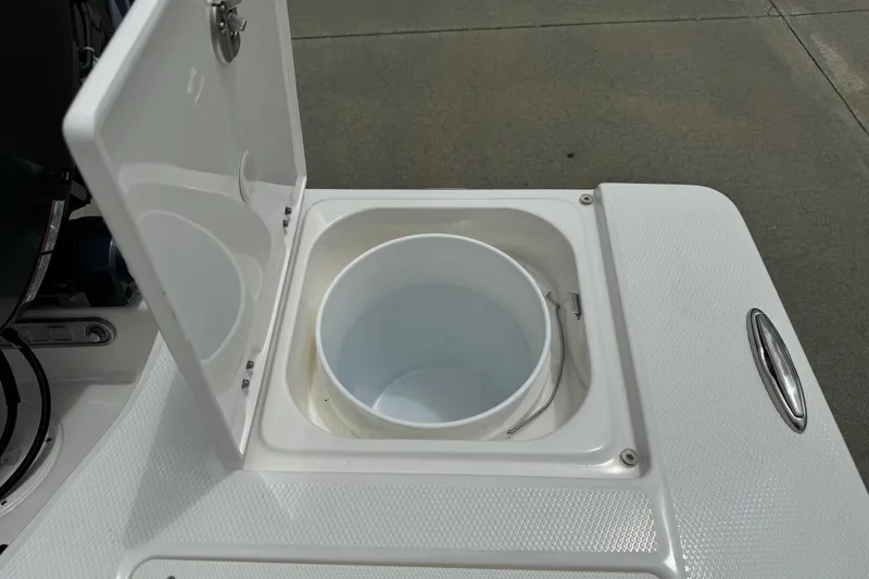 Slide: The Image of Open storage compartment on 2026 Robalo 206 Cayman boat, featuring a white bucket inside. - 17
