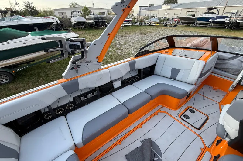 Slide: The Image of 2023 Malibu Wakesetter 23 LSV interior with orange and gray seating, docked among other boats. - 10