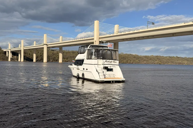 Slide: The Image of 2000 Carver 406 Aft Cabin Motor Yacht on river near bridge, under cloudy sky. - 46