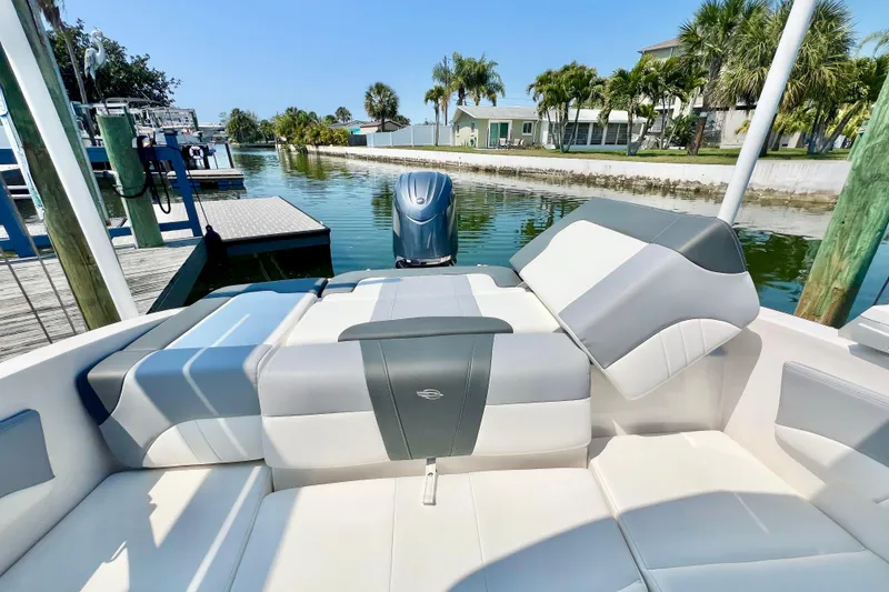 Slide: The Image of 2023 Chaparral 21 SSi OB boat interior with plush seating, docked by a scenic canal. - 11