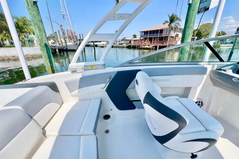 Slide: The Image of 2023 Chaparral 21 SSi OB boat interior with white seating and waterfront view. - 12