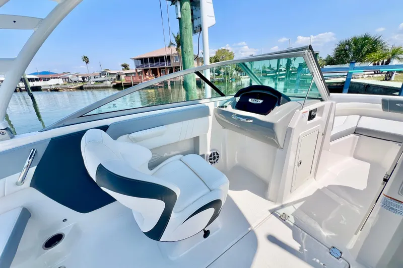 Slide: The Image of 2023 Chaparral 21 SSi OB boat interior with helm and seating, docked by the water. - 13