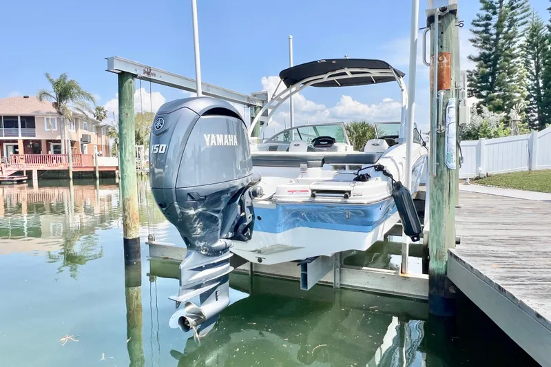 Slide: The Image of 2023 Chaparral 21 SSi OB boat with Yamaha 150 engine docked by waterfront homes. - 2