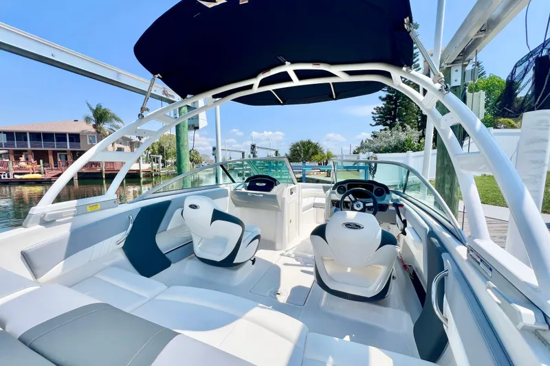 Slide: The Image of 2023 Chaparral 21 SSi OB boat interior with seating and steering wheel, docked by waterfront homes. - 9