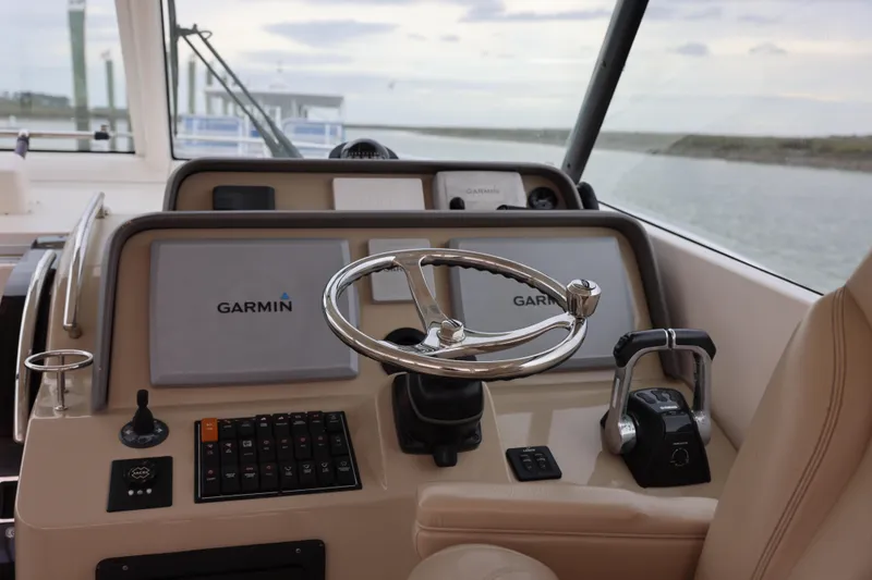 Slide: The Image of 2015 Pursuit OS 385 Offshore boat interior with seating and storage, docked by the water. - 12