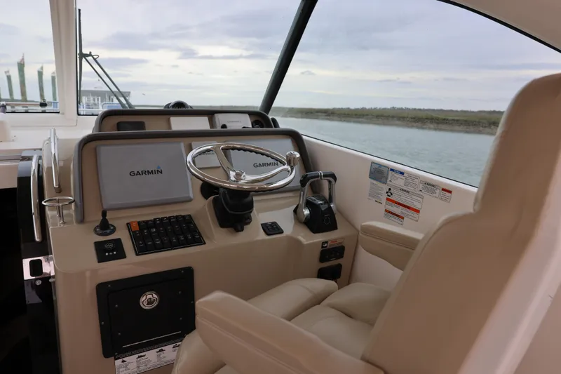 Slide: The Image of 2015 Pursuit OS 385 Offshore boat interior with seating and storage, docked on calm water. - 13