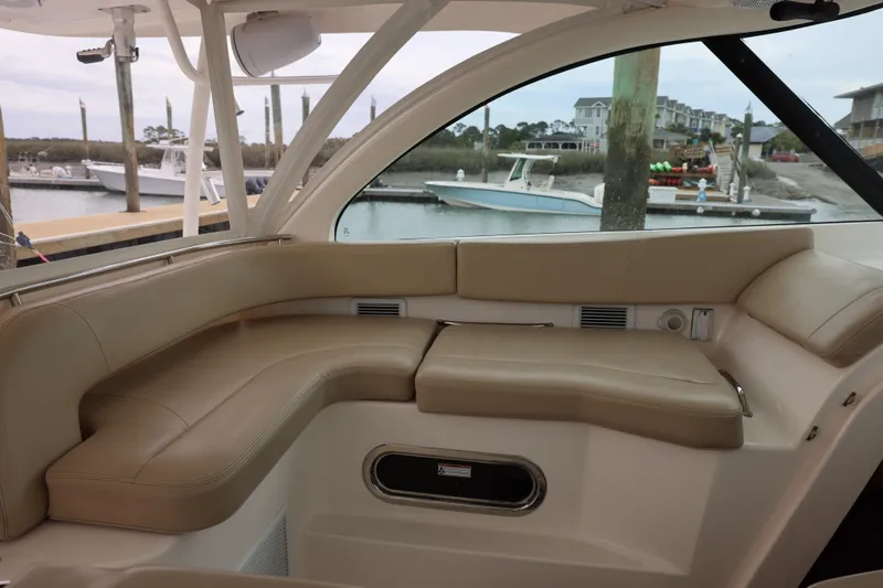 Slide: The Image of 2015 Pursuit OS 385 Offshore boat interior with beige seating and waterfront view. - 15