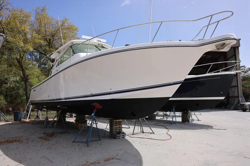 Slide: The Image of 2015 Pursuit OS 385 Offshore boat on stands, outdoors, under clear sky. - 3