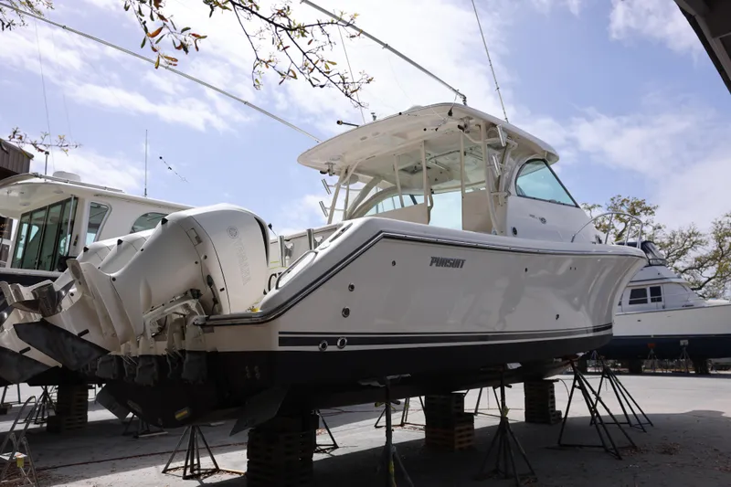Slide: The Image of 2015 Pursuit OS 385 Offshore boat on stands, viewed from the rear, with outboard engines. - 5