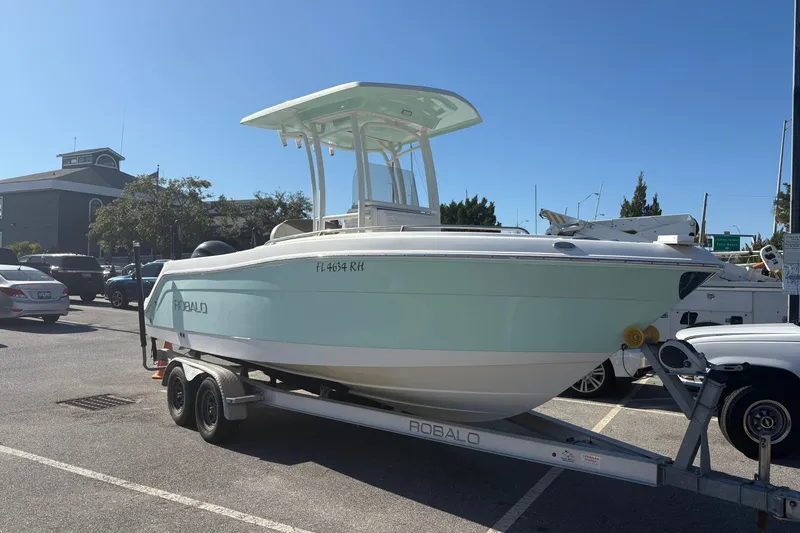 Slide: The Image of 2017 Robalo R222 boat on trailer in parking lot under clear blue sky. - 15