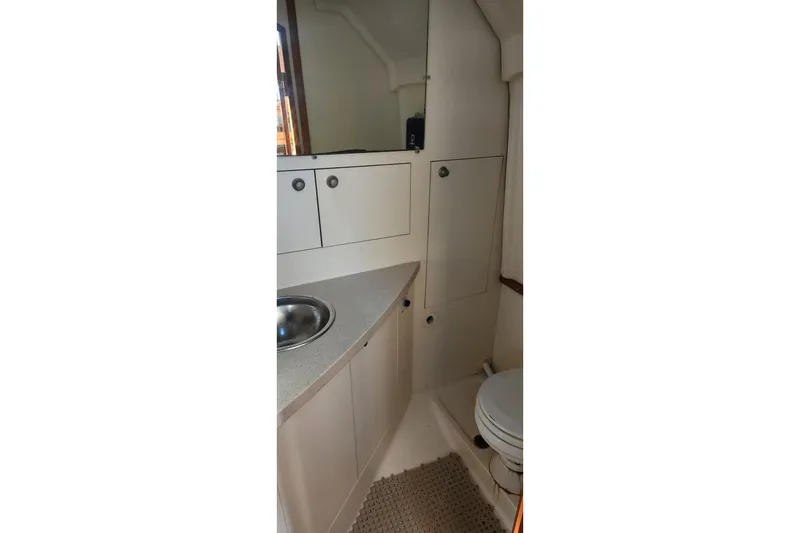 Slide: The Image of 2003 Mainship Pilot 30-II boat bathroom with sink, toilet, and storage cabinets. - 11