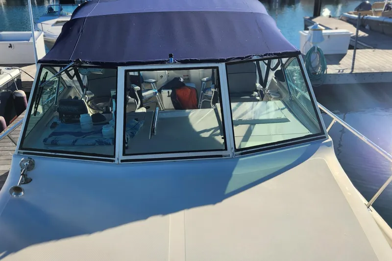 Slide: The Image of 2003 Mainship Pilot 30-II boat docked, featuring a blue canopy and spacious cockpit. - 6