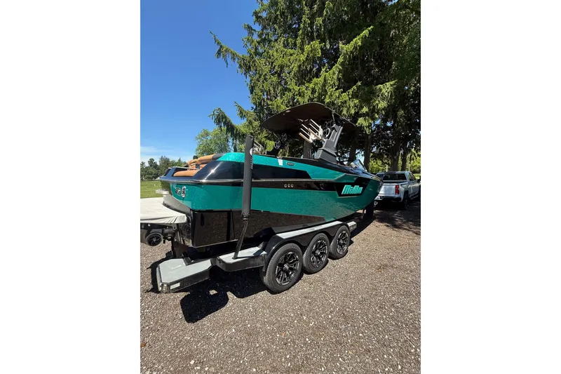 Slide: The Image of 2021 Malibu M240 boat on trailer, parked outdoors under clear blue sky. - 17