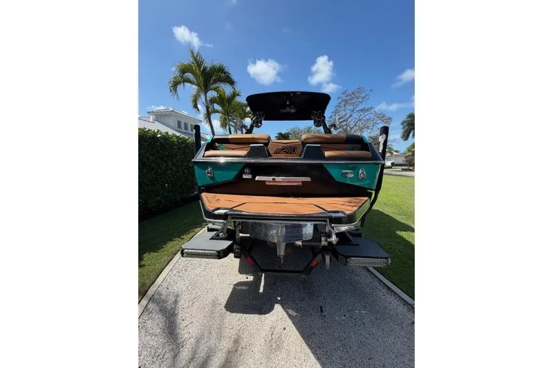 Slide: The Image of 2021 Malibu M240 boat parked on a driveway with palm trees in the background. - 5