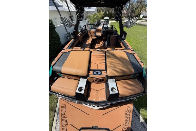 Slide: The Image of 2021 Malibu M240 boat with tan and black seating, outdoor setting. - 6
