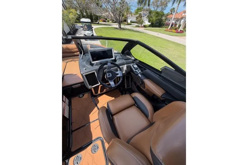 Slide: The Image of 2021 Malibu M240 boat interior with brown leather seats and modern dashboard. - 8