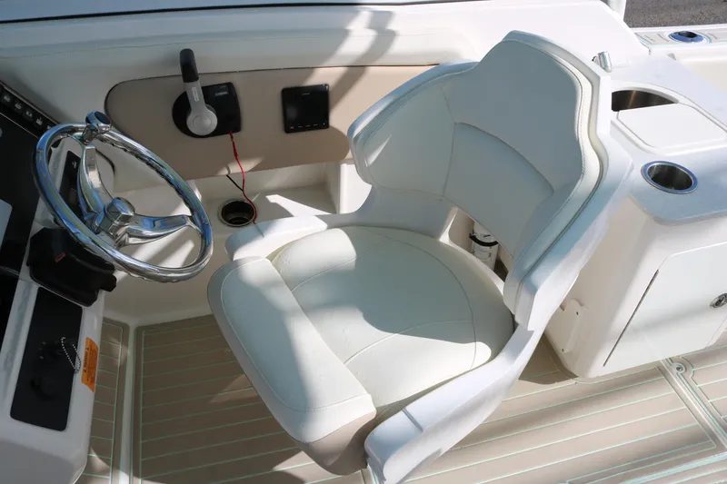 Slide: The Image of 2019 Robalo R247 Dual Console helm with white captain's chair and steering wheel. - 9