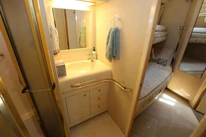 Slide: The Image of 1999 Sea Ray 500 Sundancer bathroom with sink, mirror, and adjacent cozy sleeping area. - 20