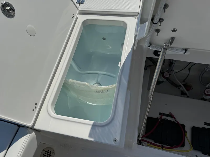 Slide: The Image of 2025 Robalo R246 CAYMAN boat storage compartment with open hatch and visible wiring. - 16