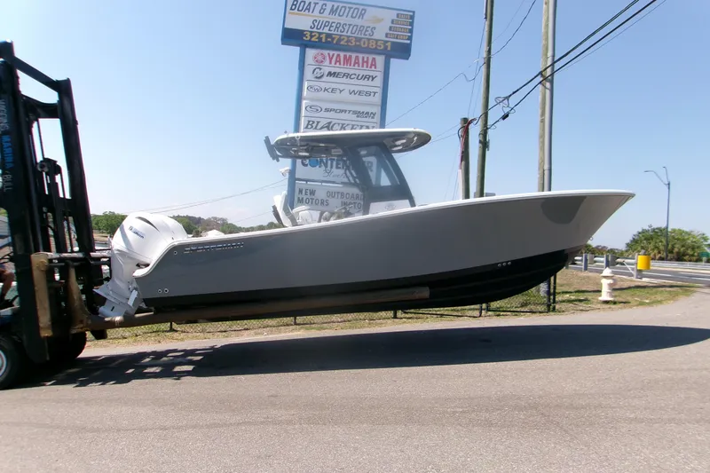 Slide: The Image of 2026 Sportsman Open 252 Center Console boat on forklift near dealership signs. - 20