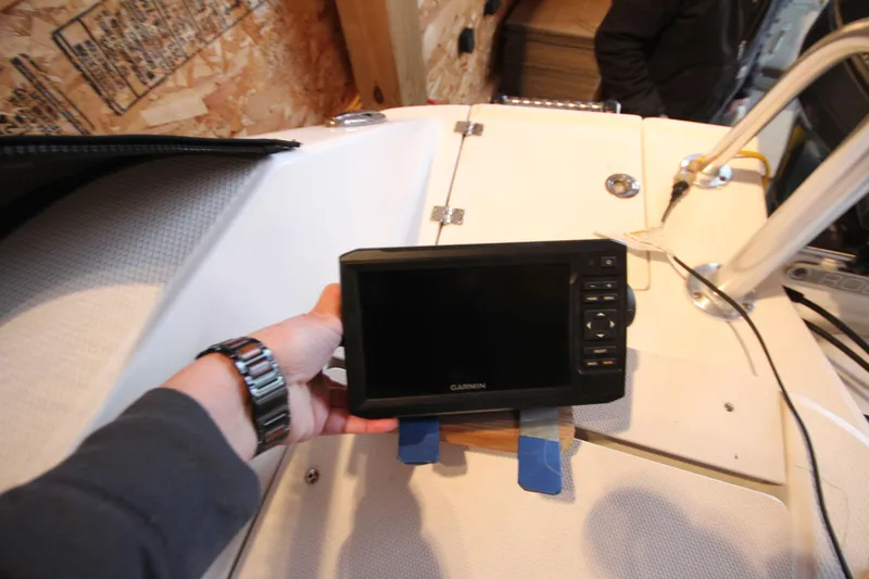 Slide: The Image of Hand holding Garmin device on 2016 Robalo R200 Center Console boat deck. - 22