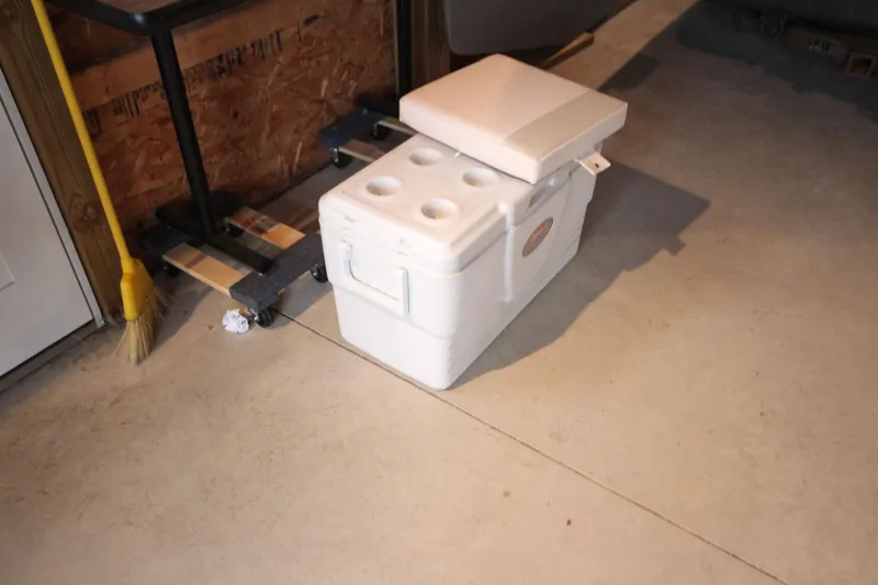 Slide: The Image of White cooler with seat cushion in a garage, next to a broom and dolly. - 23
