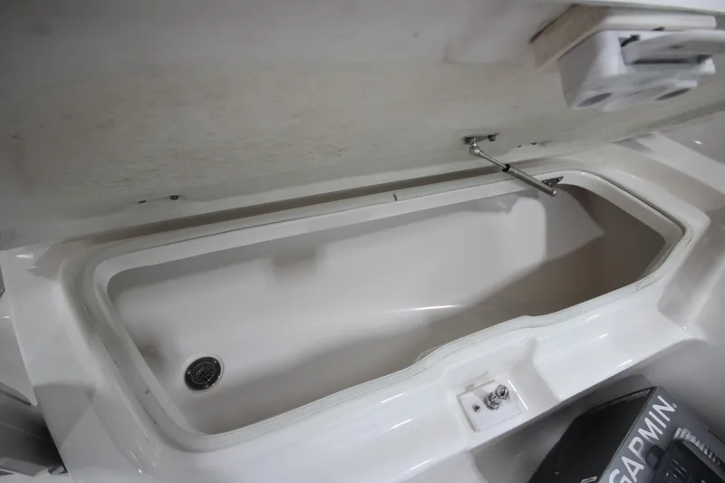 Slide: The Image of 2016 Robalo R200 Center Console storage compartment with open lid and drain plug. - 41