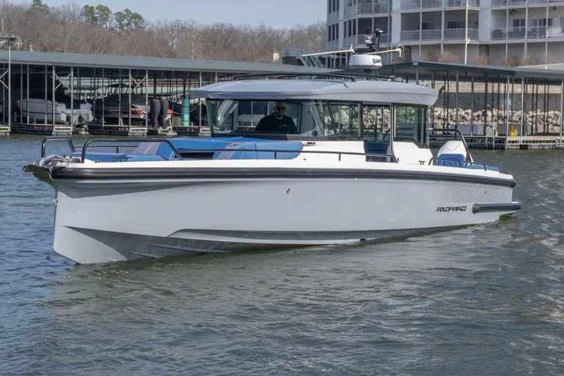Slide: The Image of 2026 Axopar 37 XC Cross Cabin boat cruising near a marina. - 2