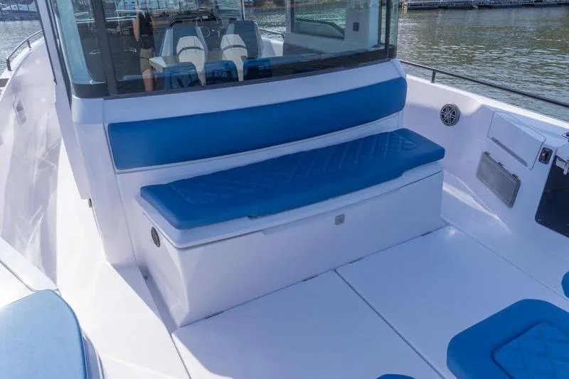 Slide: The Image of 2026 Axopar 37 XC Cross Cabin boat with blue seating, docked by the water. - 6