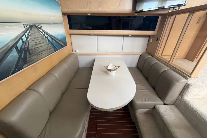 Slide: The Image of 1992 Silverton 41 Motor Yacht interior with cozy seating, table, and scenic artwork. - 25