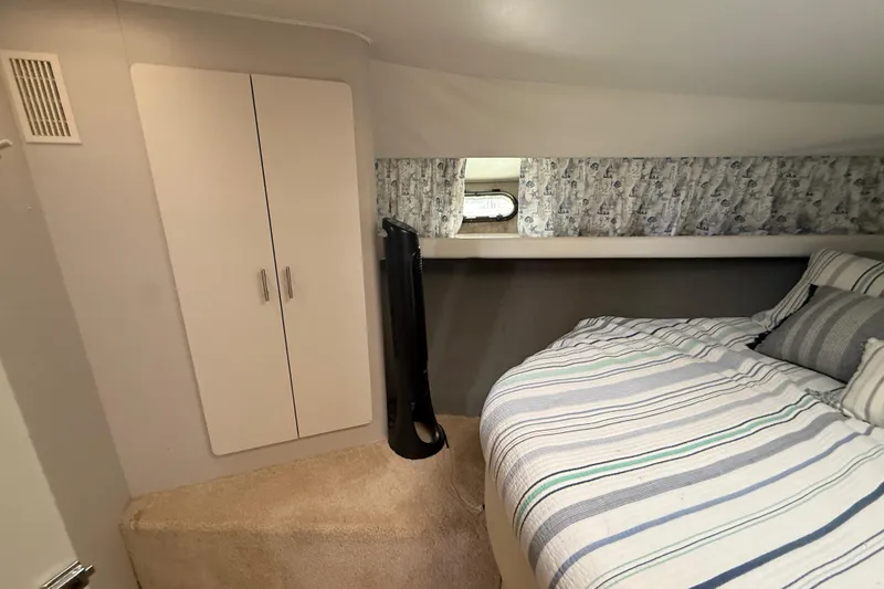 Slide: The Image of Cozy bedroom in 1992 Silverton 41 Motor Yacht with striped bedding and storage cabinet. - 33
