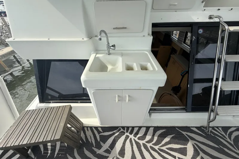 Slide: The Image of Outdoor sink area on a 1992 Silverton 41 Motor Yacht with patterned rug and wooden stool. - 7