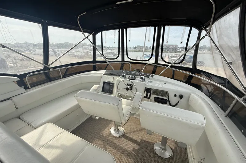 Slide: The Image of Interior view of 1992 Silverton 41 Motor Yacht helm with white seating and panoramic windows. - 9