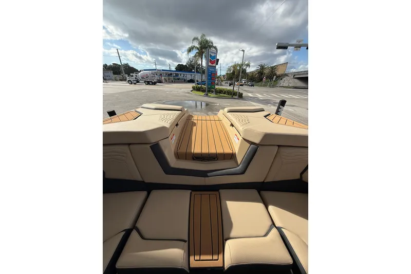 Slide: The Image of 2026 Nautique Super Air Nautique G25 Coastal Edition interior with tan seating at a gas station. - 7