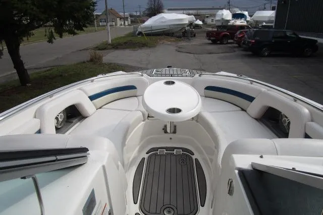 Slide: The Image of 2016 Chaparral 264 Sunesta boat interior with seating and table, parked outdoors. - 12