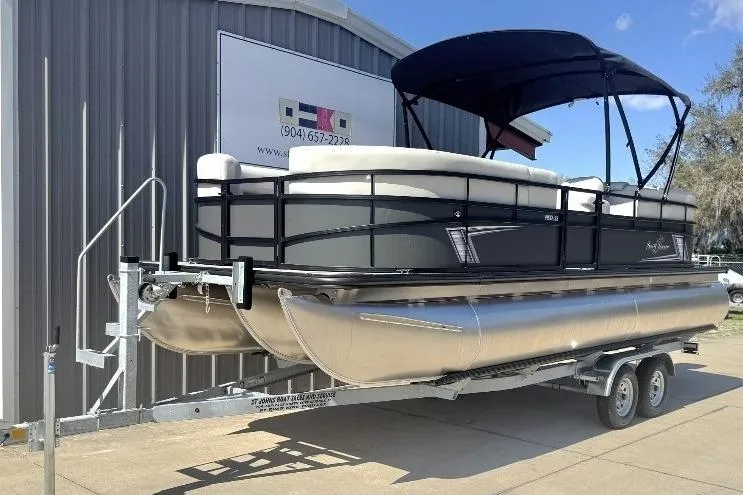 Slide: The Image of 2026 SunChaser Vista LR DH pontoon boat on trailer, parked outside a metal building. - 6